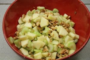 Waldorf saláta készítése: alma, zellerszár, dió tálban